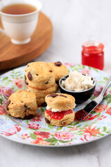 Scones on a Flowery Plate, a jar of Strawberry Jam and a Cup of Tea
