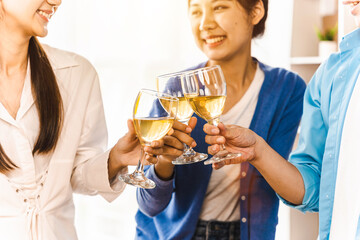 Happy Asian people eating pizza and cheering with white wine at coworking office during break. Food delivery and team work concept