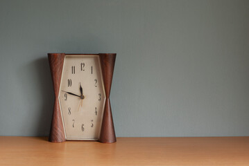 Retro alarm clock on wooden table and grey background.