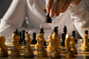 Faceless caucasian woman in white shirt playing chess. 