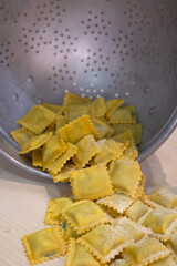 Freshly Made Raw Tortelli Leaking from a Metal Colander.