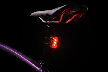 Close-up of illuminated bicycle tail light. Red bicycle tail light