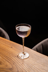 Gently lilac drink in a beautiful thin glass, decorated with walnut crumbs. Cocktail on a wooden table. Bar or restaurant concept