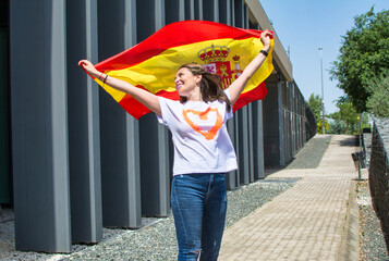 Young woman smiling with the Spanish flag. Happy young adult waving a flag. Lifestyle
