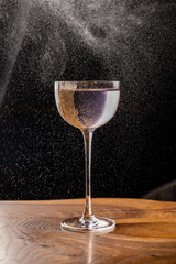 Gently lilac drink in a beautiful thin glass, decorated with nut crumbs with splashes on the...