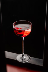 Red cocktail in a beautiful thin glass decorated with smears of glucose. Bar or restaurant concept