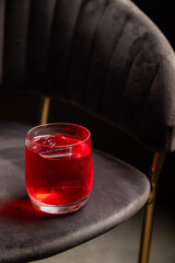 A red cocktail with a block of ice stands on a chair. Bar or restaurant concept