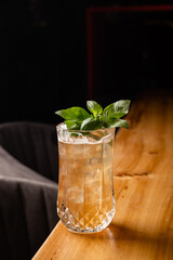 Cool refreshing drink with ice and leaves. Cocktail on a wooden table. Bar or restaurant concept