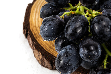 Black Grapes isolated in white background; water drops; studio lighting; macro detailing, negative space for copy