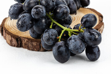 Black Grapes isolated in white background; water drops; studio lighting; macro detailing, negative space for copy