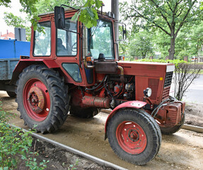 Old red tractor standing at the road construction