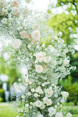 Beautiful white wedding arch decorated with white flowers outdoors