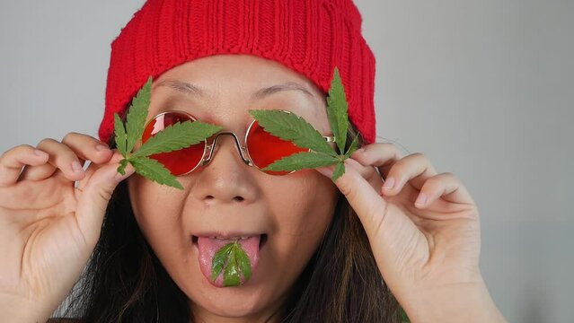 Funny asian girl with green hemp leaves.