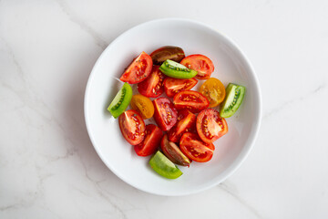 Overhead view of sliced tomatoes for salad in white bowl