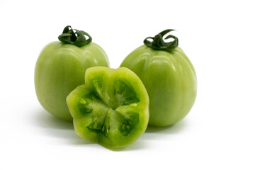 Whole and halved fresh green unripe tomatoes isolated on white background