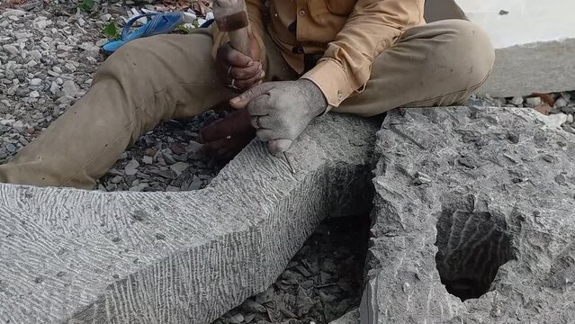Indian Stone carving Artist Carving A Beautiful Abstract Sculpture From Black Granite Stone.