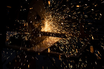 Lots of sparks from cutting metal in dark. Lights fly in different directions. Industrial...