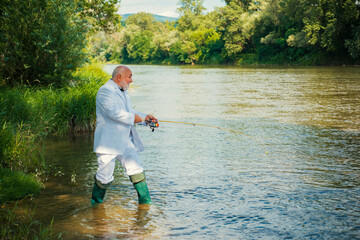 Fisherman senior rich businessman in suit caught a fish. Man fishing on river.