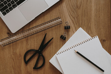 Laptop, notebook, stationery on brown wooden table. Flat lay, top view aesthetic home office workspace
