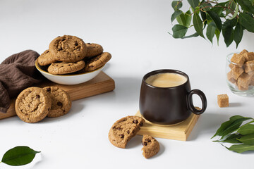 A cup of coffee, chocolate chip cookies next to and in the background.