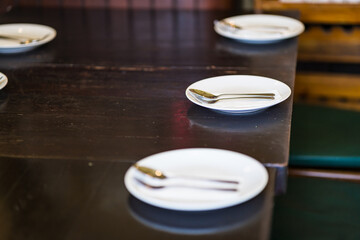 silver spoon and fork with white dish on wooden background.