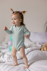 little girl having fun playing on the bed with balloons