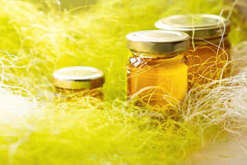 Obraz na płótnie Canvas Honey in glass jars with flowers background.