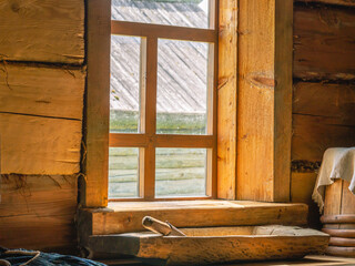 Wooden trough for cooking minced meat. Antique wooden objects in the kitchen of an old house built in the 19th century. A window in an old log house