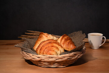 Warm fresh buttery croissants in wicker basket. Breakfast, bread bakery products cafe concept