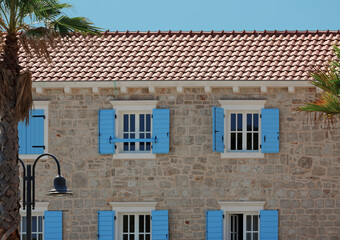 Facade of a old mediterranean building with windows decorated with blue shutters. Croatia