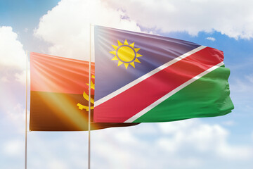 Sunny blue sky and flags of namibia and angola