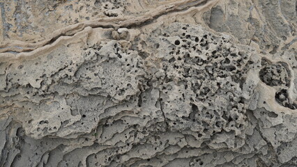 Volcanogenic rock slabs on the seashore. Natural rocky breakwater at seashore