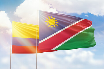 Sunny blue sky and flags of namibia and colombia
