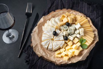 Cheese assortment on  plate with red wine on  a dark background.