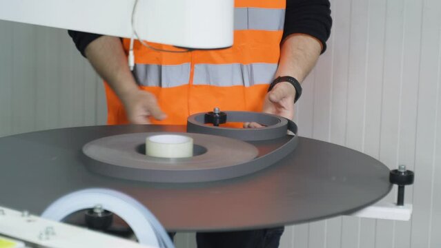 Furniture manufacture. Filling the machine with a PVC edge for edging parts made of chipboard. Close-up.