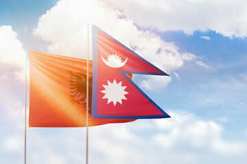 Sunny blue sky and flags of nepal and albania