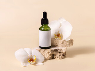 Obraz na płótnie Canvas Green dropper glass bottle near white orchid flowers on light yellow, Mockup. Skincare product