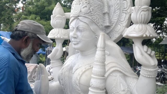 Indian craftsman carving traditional Hindu Goddess Lakshmi or Laxmi White marble stone Sculpture or statue For Sale, Using Hammer And Chisel, hand moving.
