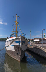 Fototapeta na wymiar Old fishing boat and a steam boat at the pier on the island Kungsholmen a sunny summer day in Stockholm