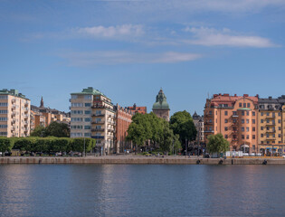 Obraz premium Apartment houses at the waterfront and the tower of a court house on the island Kungsholmen a sunny summer day in Stockholm