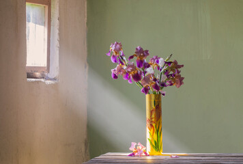 irises in  beautiful glass vase in old grunge interior