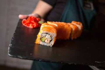 Philadelphia sushi roll with salmon, cucumber, avocado, cream cheese. Sushi menu. Japanese food. On a plate. On dark background.
