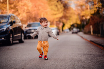 Little toddler boy walking down the street in spring-autumn outfit