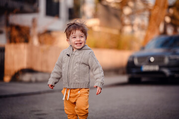 Little toddler boy walking down the street in spring-autumn outfit