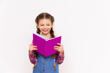 Obraz premium Reading a book. A little girl is reading a book on a white isolated background. Children's education.
