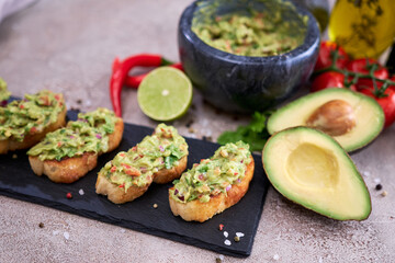 bruschetta with freshly made guacamole on grey concrete background
