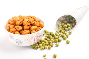 Fried coated peanuts and green peas on white background. Delicious snack.