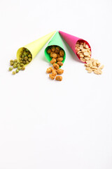Indian snack, dry spicy nuts in paper cone on white background.