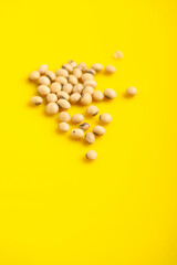 Dry soybean seed on yellow background.