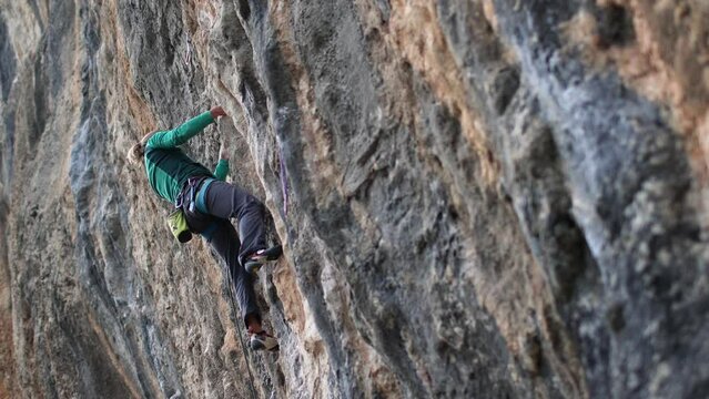 The girl climbs the rock, The climber trains on natural terrain,  A woman overcomes a difficult climbing route against the background of a blue sky